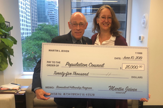 Martin Jeivan and Julia Bunting holding a large check. Ideas. Evidence. Impact.