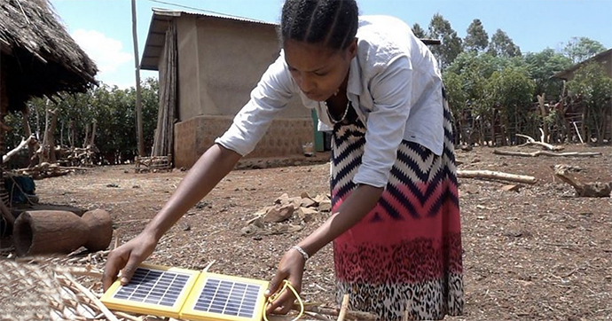 a young woman holding solar panels Ideas. Evidence. Impact.