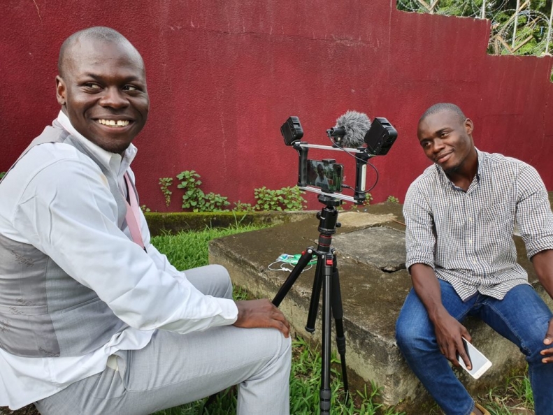 two smiling men holding an interview outside