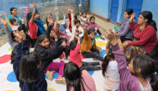 Guatemalan girls play the game Twister in a courtyard with their teacher.