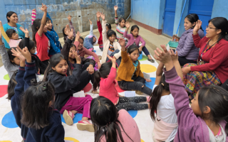 Girls mentor twister_lowres – Population Council Guatemalan girls play the game Twister in a courtyard with their teacher.