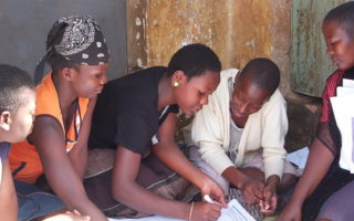 Nia – Population Council women in a group filling out paperwork