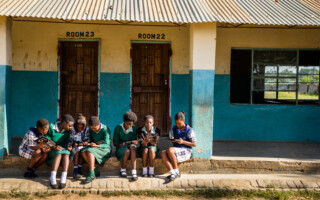 _L4A9308_HR – Population Council Girls reading in front of building.