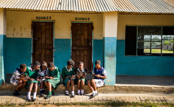_L4A9308_HR – Population Council Girls reading in front of building.